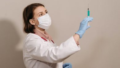 a physician in white coat looking at a syringe
