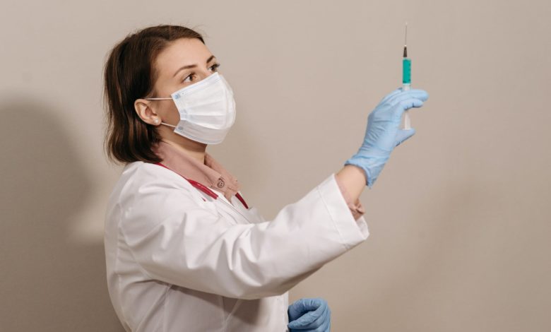 a physician in white coat looking at a syringe