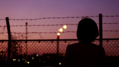 silhouette of person in front of fence
