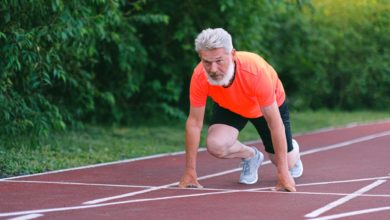 serious strong elderly man starting for run in racetrack