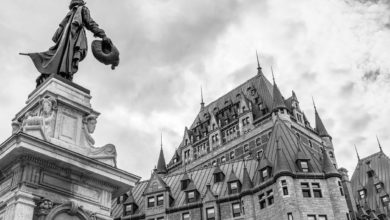 grayscale photo of statue of man on top of concrete tower