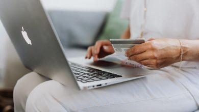 person using a macbook and holding a credit card