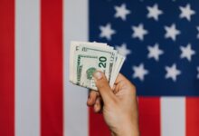 crop person showing pack of dollars against american flag
