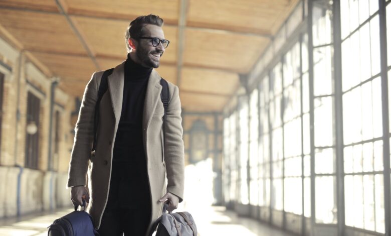 man in brown robe carrying bag smiling