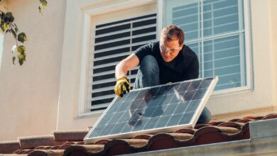 man with gloves holding solar panels on the roof